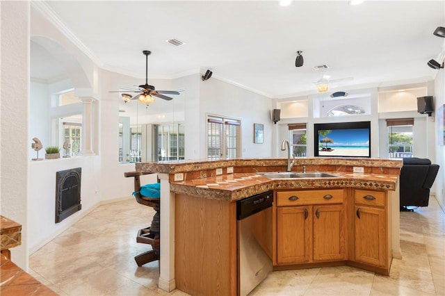 kitchen featuring stainless steel dishwasher, ornamental molding, ceiling fan, sink, and a center island with sink