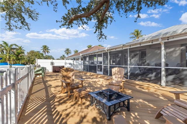 view of patio with a wooden deck, a sunroom, and an outdoor fire pit