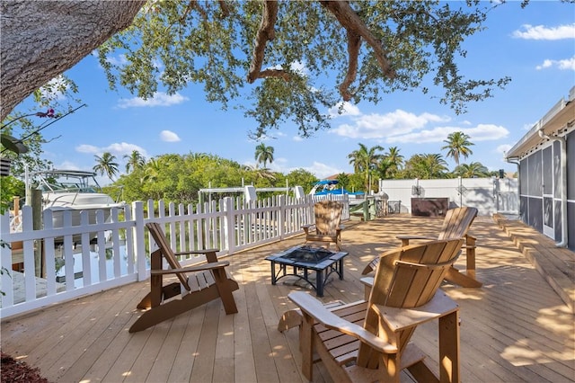 deck with a sunroom and a fire pit