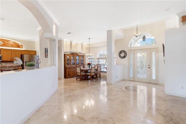 entryway with decorative columns, a chandelier, and ornamental molding