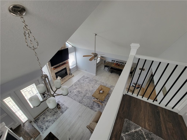 living room featuring hardwood / wood-style floors, ceiling fan, a fireplace, and lofted ceiling