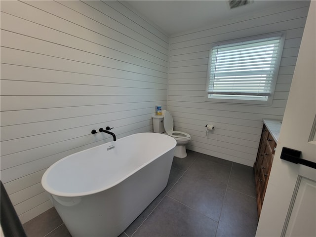 bathroom featuring toilet, a bathtub, wood walls, and tile patterned floors