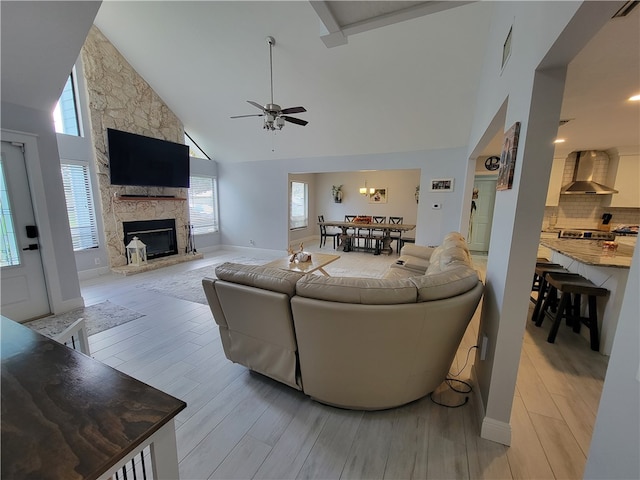 living room with high vaulted ceiling, a healthy amount of sunlight, light hardwood / wood-style floors, and a fireplace