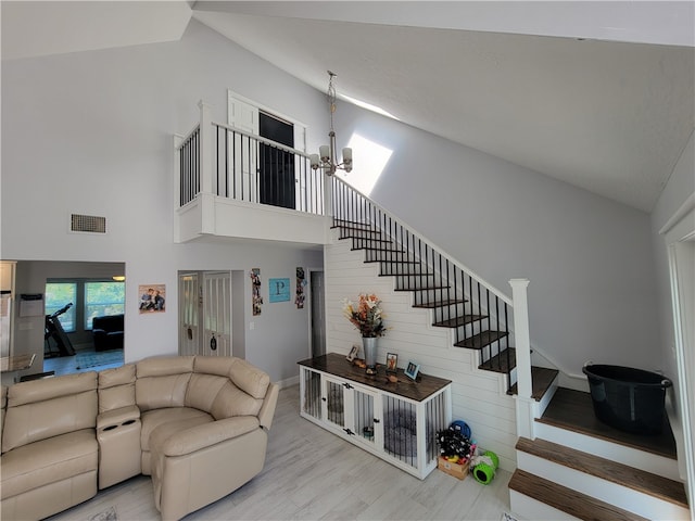 living room with high vaulted ceiling, light hardwood / wood-style floors, and a notable chandelier