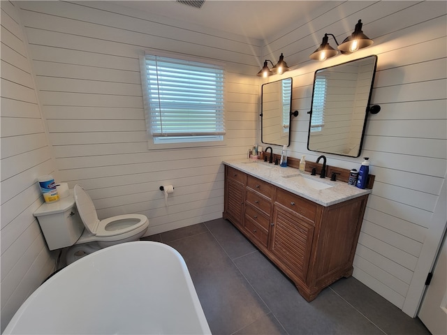 bathroom featuring vanity, wooden walls, tile patterned flooring, a bathing tub, and toilet