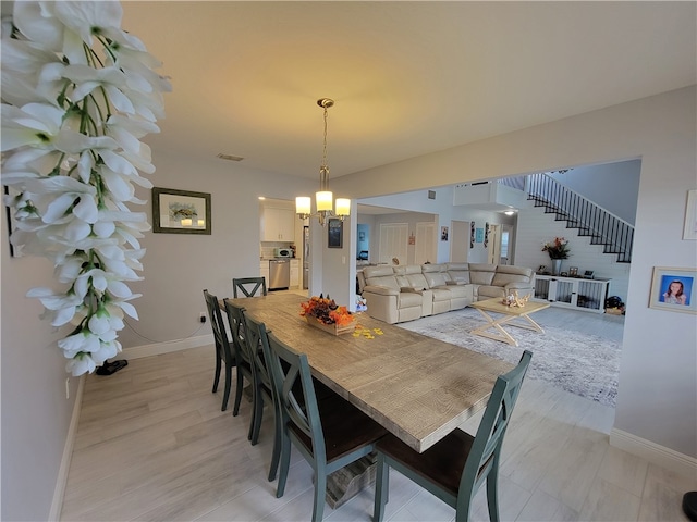 dining room with light hardwood / wood-style flooring and an inviting chandelier