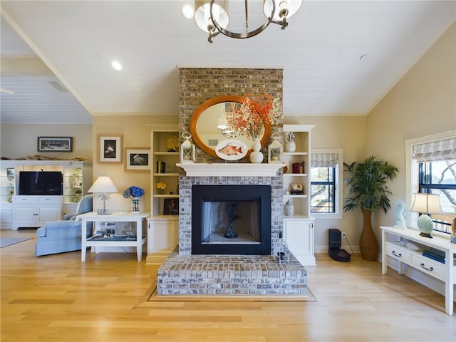 living room featuring vaulted ceiling, light hardwood / wood-style floors, a brick fireplace, and a notable chandelier