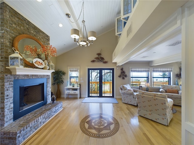 living room with wood-type flooring, a brick fireplace, a healthy amount of sunlight, and french doors