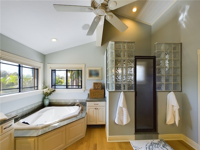 bathroom featuring hardwood / wood-style flooring, vanity, separate shower and tub, and vaulted ceiling