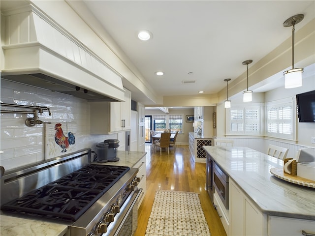 kitchen with white cabinetry, light stone countertops, custom range hood, and appliances with stainless steel finishes