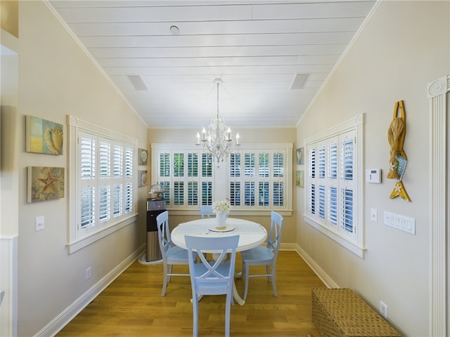 dining space with hardwood / wood-style floors, vaulted ceiling, and ornamental molding