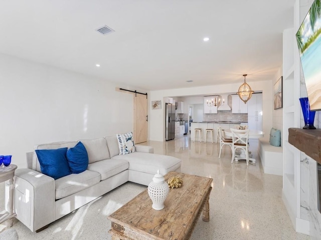 living room featuring light speckled floor, a barn door, visible vents, and recessed lighting