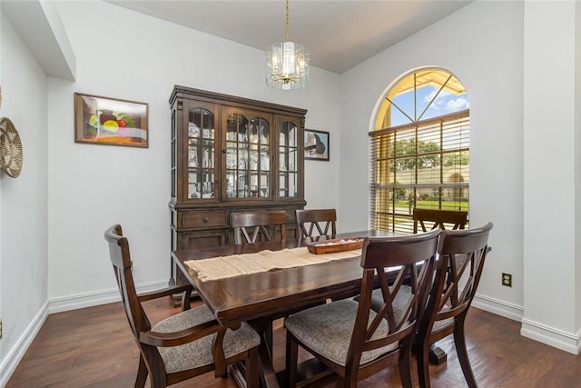 dining room with an inviting chandelier, lofted ceiling, and dark wood-type flooring