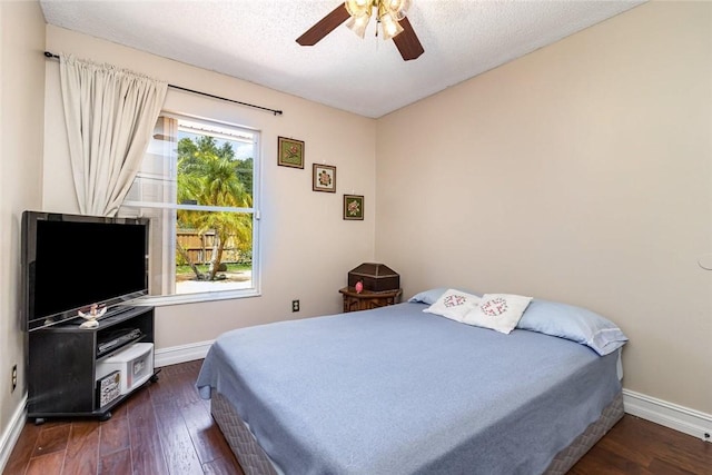 bedroom with multiple windows, dark hardwood / wood-style flooring, and a textured ceiling