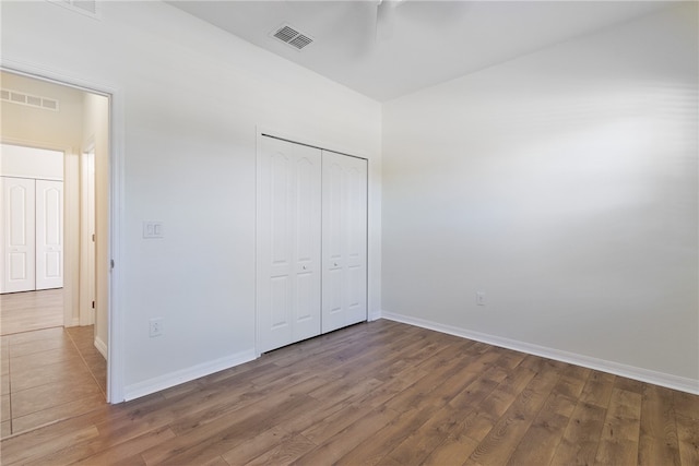 unfurnished bedroom with dark hardwood / wood-style floors, a closet, and ceiling fan