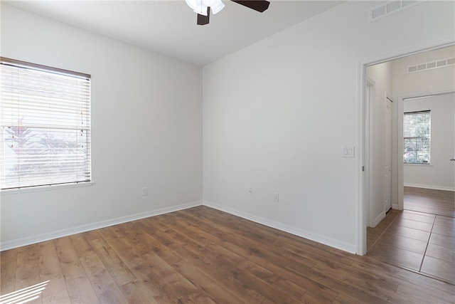 spare room with a wealth of natural light, ceiling fan, and dark wood-type flooring