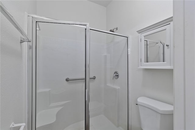 bathroom with a shower with shower door and toilet