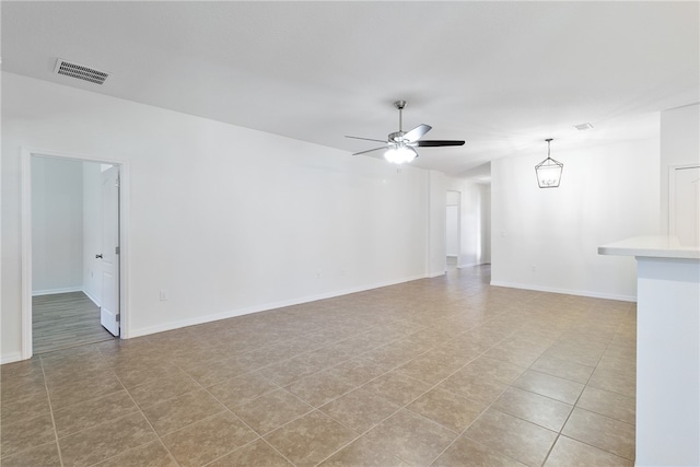 tiled spare room featuring ceiling fan with notable chandelier