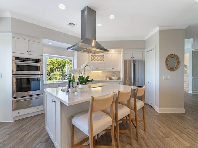 235 Osprey Ct, Vero Beach, FL 32963 - kitchen with a warming drawer, island exhaust hood, appliances with stainless steel finishes, tasteful backsplash, and ornamental molding