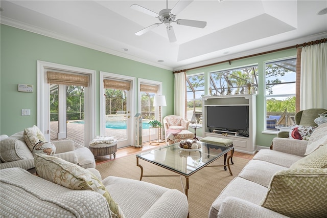 sunroom / solarium with ceiling fan and a tray ceiling