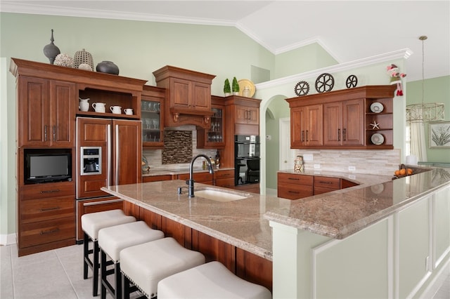 kitchen featuring brown cabinets, a kitchen breakfast bar, a peninsula, open shelves, and a sink