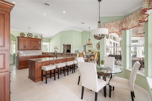 dining space featuring vaulted ceiling, plenty of natural light, visible vents, and crown molding