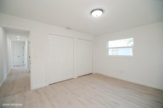 7645 58th Ave, Vero Beach, FL 32967 - unfurnished bedroom featuring baseboards, wood finished floors, and two closets