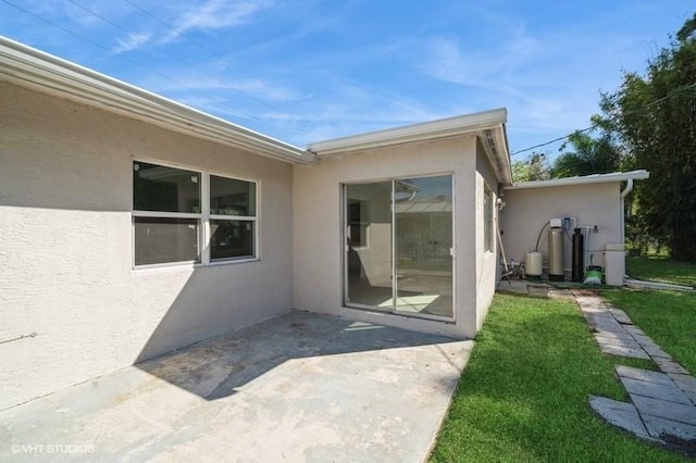 7645 58th Ave, Vero Beach, FL 32967 - view of exterior entry featuring stucco siding, a lawn, and a patio