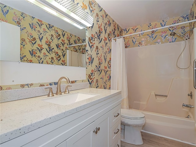 bathroom with wallpapered walls, toilet, wood finished floors, shower / bath combination with curtain, and vanity