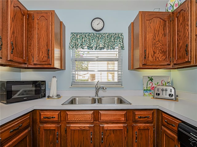 kitchen featuring brown cabinets, light countertops, a sink, and black appliances