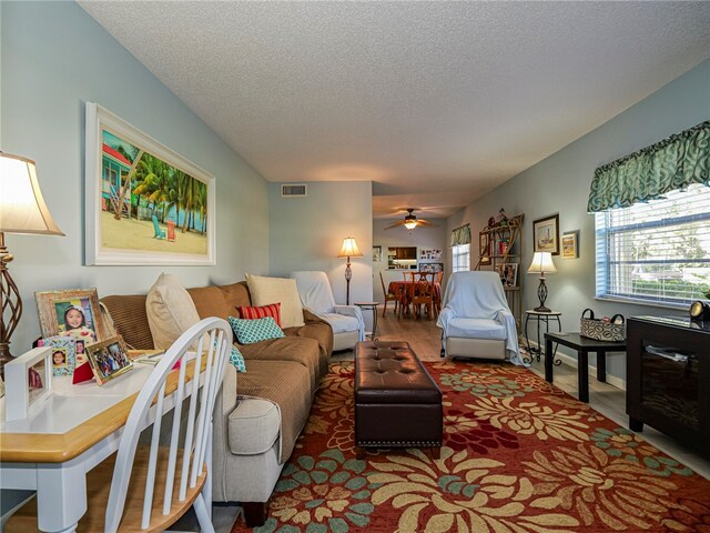 living room featuring visible vents, ceiling fan, and a textured ceiling