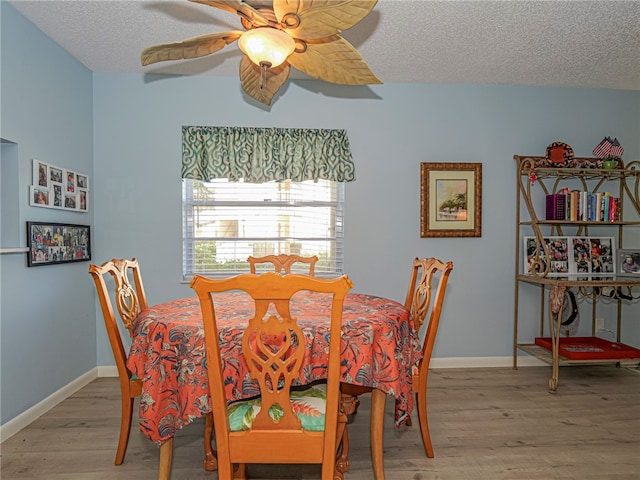 dining room featuring a textured ceiling, light wood finished floors, a ceiling fan, and baseboards