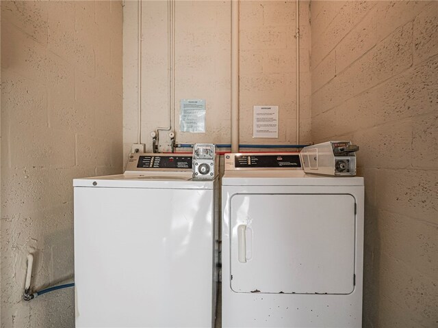 common laundry area featuring washer and clothes dryer and concrete block wall