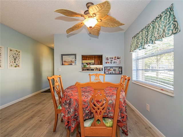 dining room with ceiling fan, a textured ceiling, light wood-type flooring, and baseboards