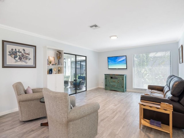 living area with light wood-style floors, visible vents, crown molding, and baseboards