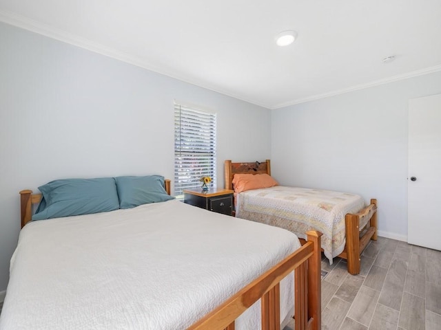 bedroom featuring light wood finished floors, baseboards, and ornamental molding