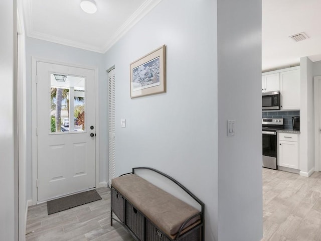 foyer entrance featuring ornamental molding, light wood-type flooring, visible vents, and baseboards