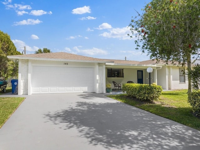 single story home with an attached garage, a front yard, concrete driveway, and stucco siding