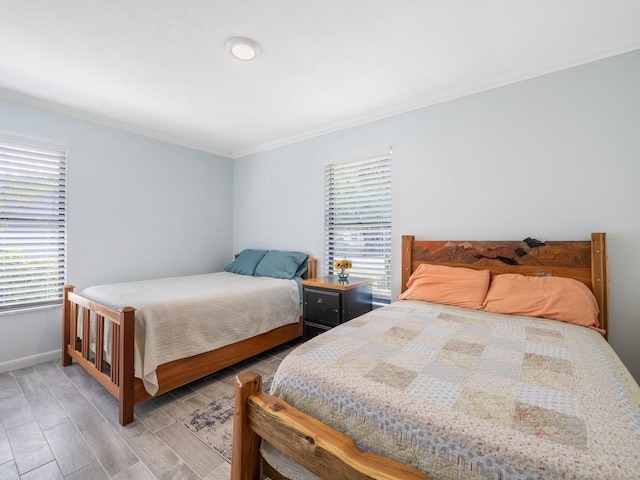 bedroom with baseboards, crown molding, and wood finished floors