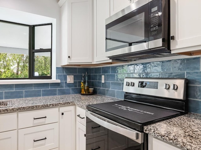 kitchen with white cabinetry, tasteful backsplash, appliances with stainless steel finishes, and light stone counters