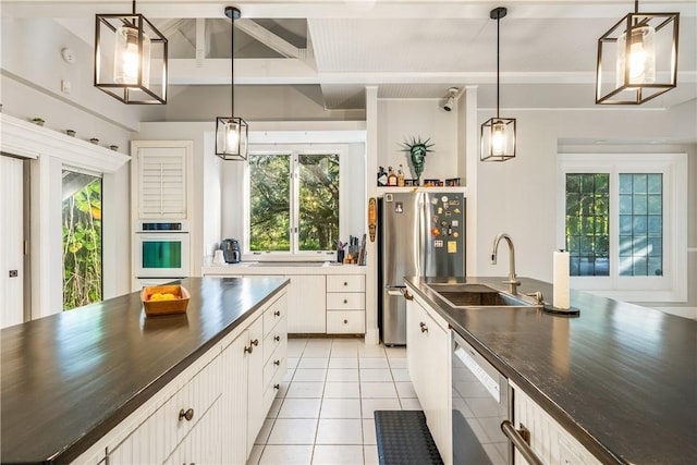 kitchen with pendant lighting, white cabinets, sink, appliances with stainless steel finishes, and beam ceiling