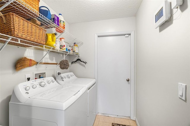 laundry room featuring a textured ceiling, independent washer and dryer, light tile patterned flooring, and laundry area