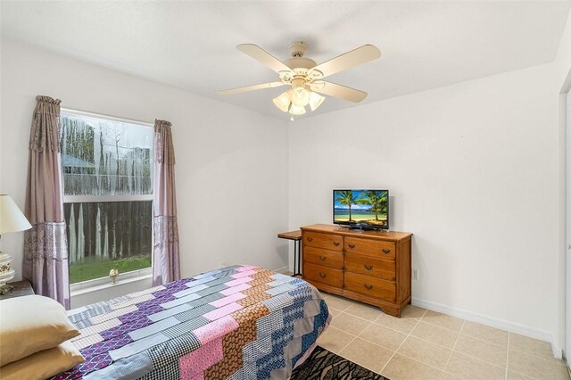 bedroom featuring baseboards, light tile patterned flooring, and a ceiling fan