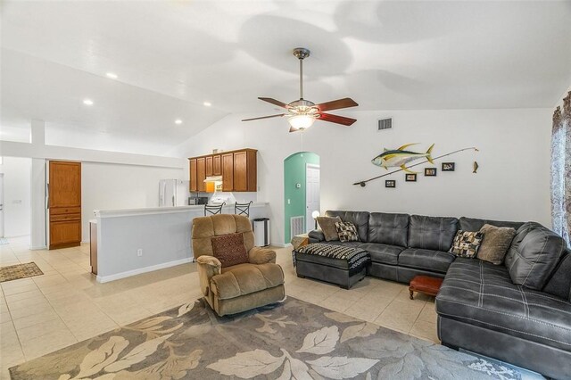 living area with visible vents, vaulted ceiling, light tile patterned floors, arched walkways, and a ceiling fan