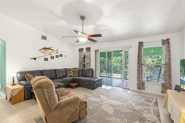 living room featuring visible vents, a ceiling fan, light tile patterned flooring, baseboards, and vaulted ceiling