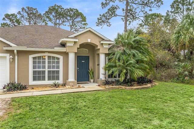 view of front of property featuring stucco siding, a front yard, and roof with shingles