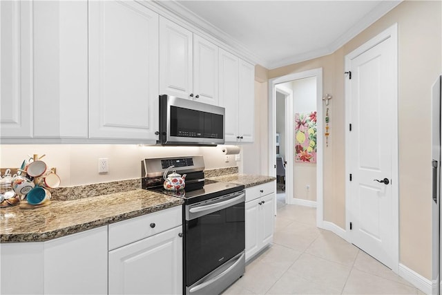 kitchen featuring ornamental molding, dark stone counters, stainless steel appliances, white cabinetry, and light tile patterned flooring