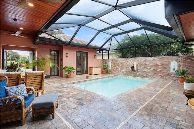 view of swimming pool with glass enclosure, ceiling fan, french doors, and a patio