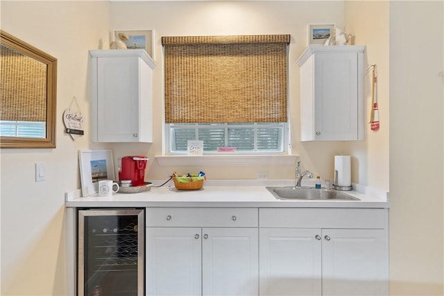 kitchen with white cabinetry, sink, and beverage cooler