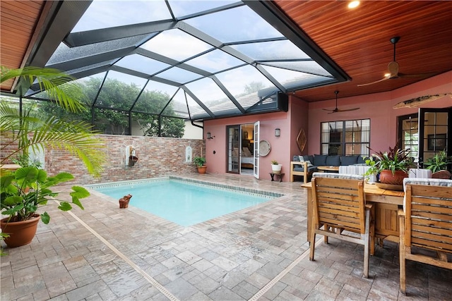 view of pool featuring outdoor lounge area, a patio area, ceiling fan, and a lanai